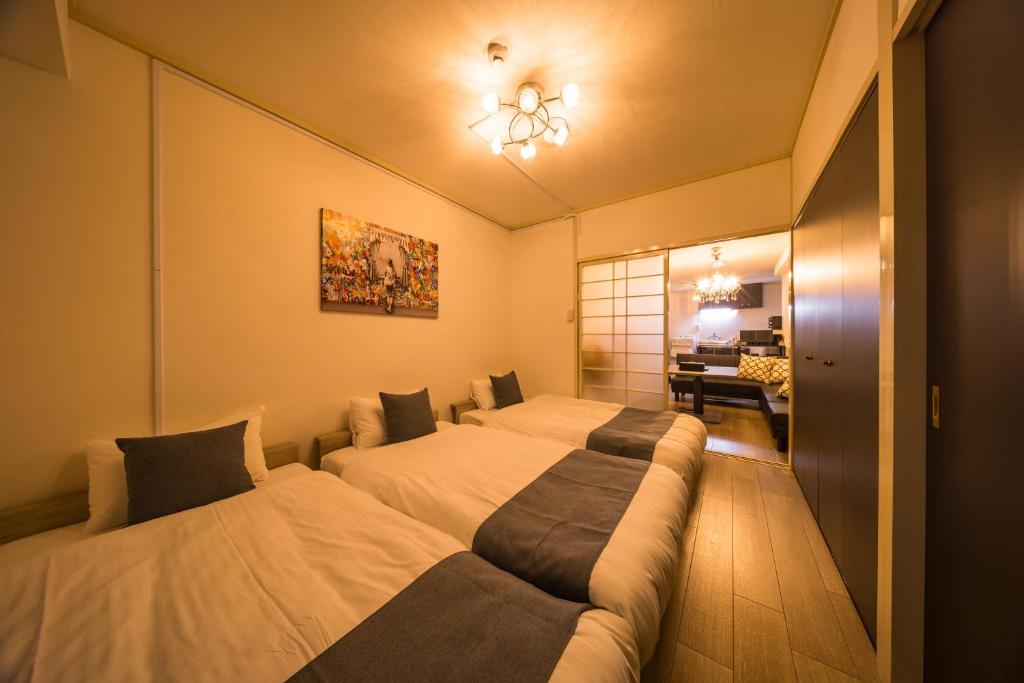 a bedroom with two beds and a desk at mikiHOTEL本川町303 in Hiroshima