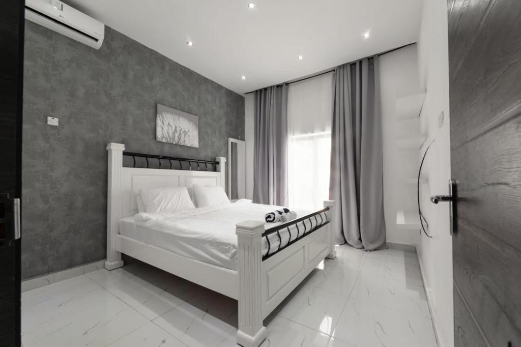 um quarto com uma cama branca e uma janela em chamis apartment em Bijilo