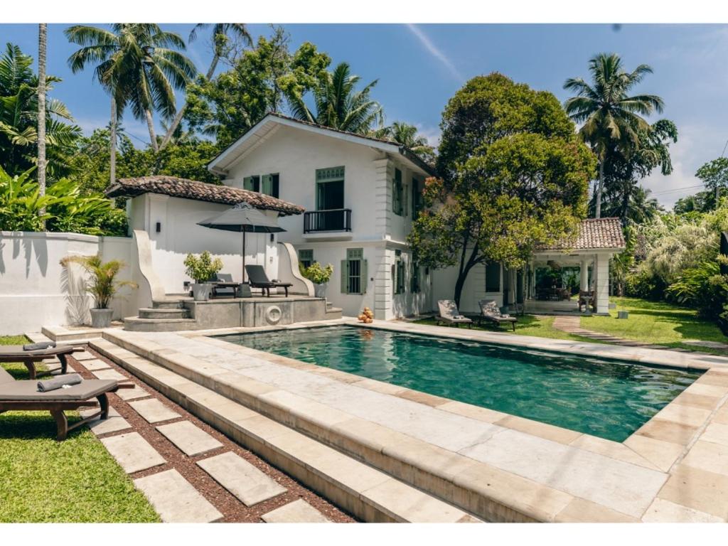 a swimming pool in front of a house at Wijaya Giri walkable to beach pool chef in Ahangama