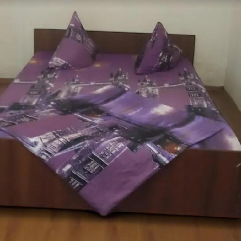 een bed met een paars dekbed en kussens bij Мономаха 27 Центр in Dnipro