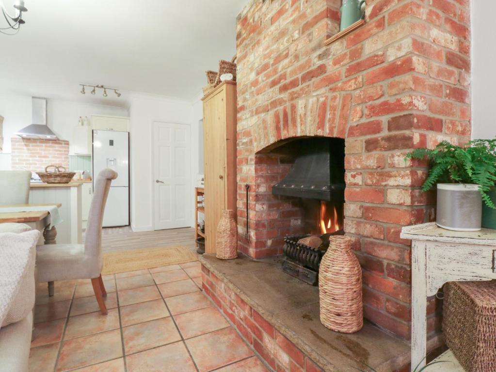 een stenen open haard in een woonkamer met een fornuis bij Berkley Cottage in Coggeshall
