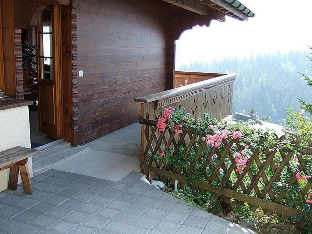 a porch of a house with a wooden fence and flowers at Chalet Hofer in Hasliberg Wasserwendi