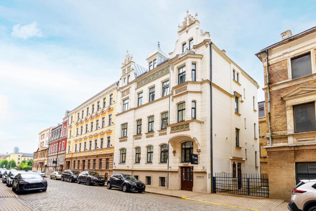 a large white building with cars parked on a street at RIJA Riga City Centre Hotel in Riga