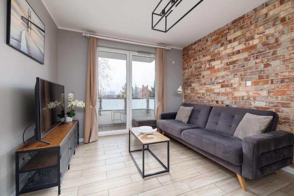 a living room with a couch and a brick wall at Modern 2-Bedroom Apartment with Remote Workspace in Katowice by Noclegi Renters in Katowice