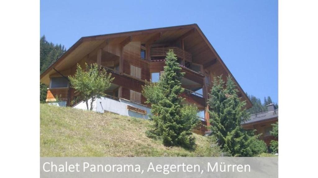 a building on a hill with trees in front of it at Panorama 2 Bett Wohnung in Mürren
