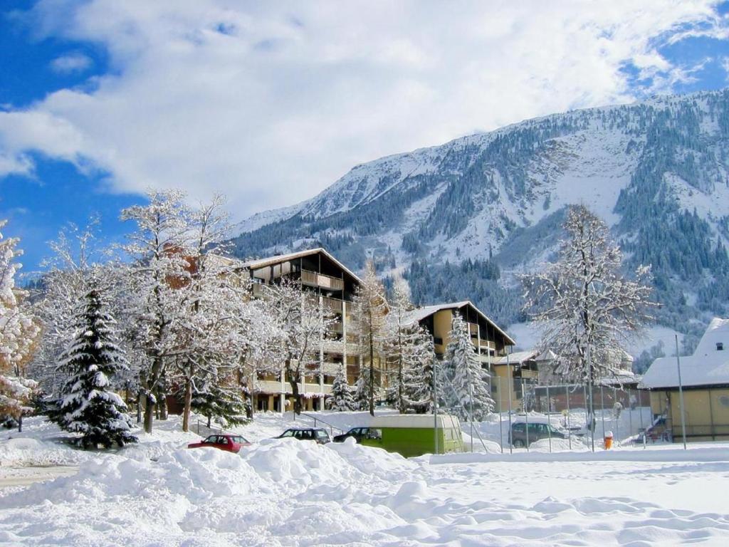un edificio cubierto de nieve frente a una montaña en Gemütliche Ferienwohnung Im Disentiserhof, en Disentis