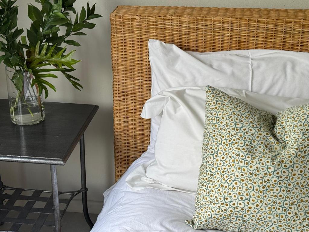a bed with a pillow and a table with a plant at De Eike in Stellenbosch