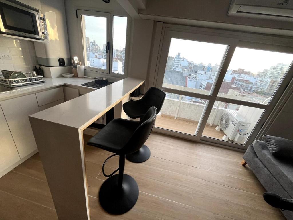 a kitchen with a counter and two chairs in front of a window at Stuart's Apartment in Mar del Plata