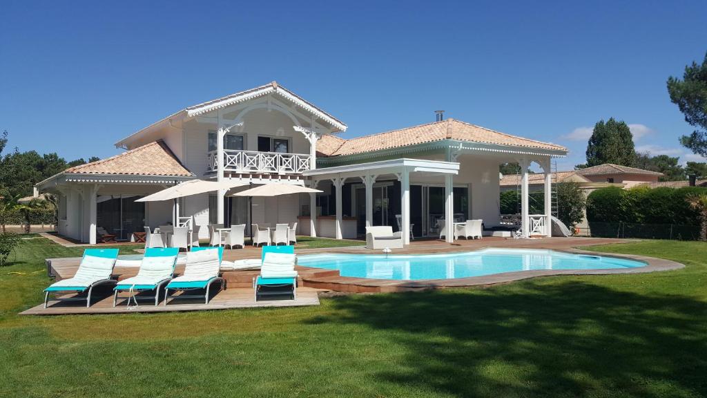 une maison avec des chaises et une piscine dans l'établissement Villa BORA BORA, à Gujan-Mestras