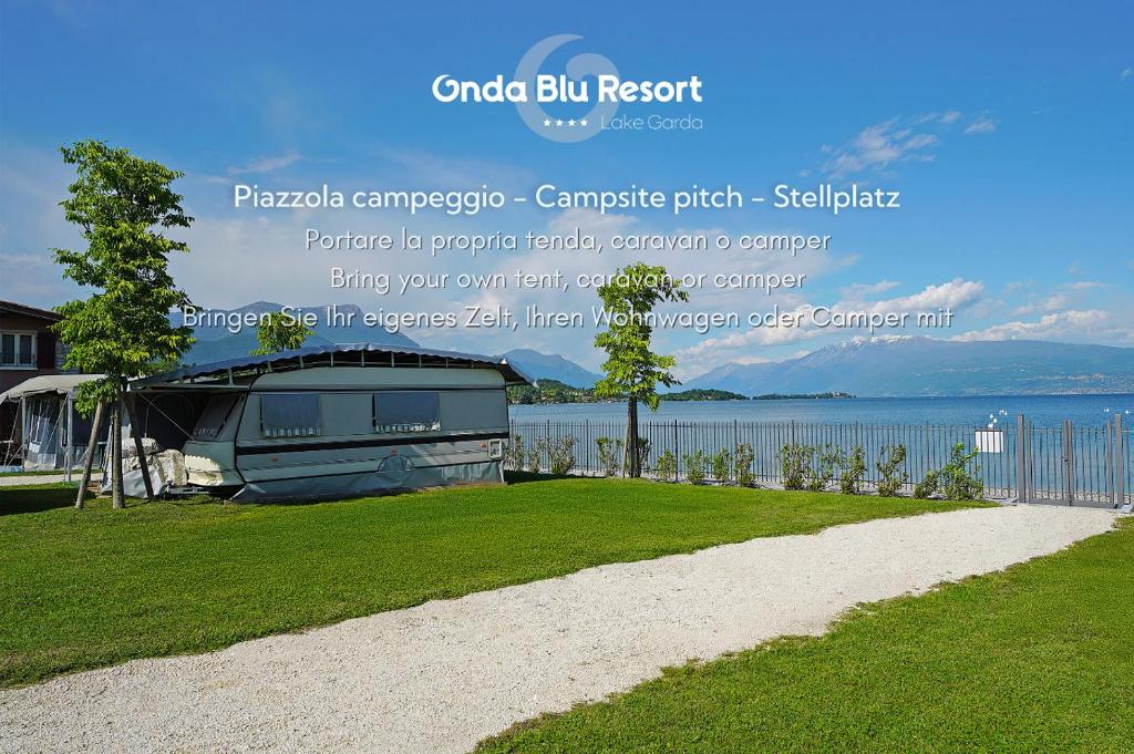 a sign for a house next to the water at Camping Onda Blu in Manerba del Garda
