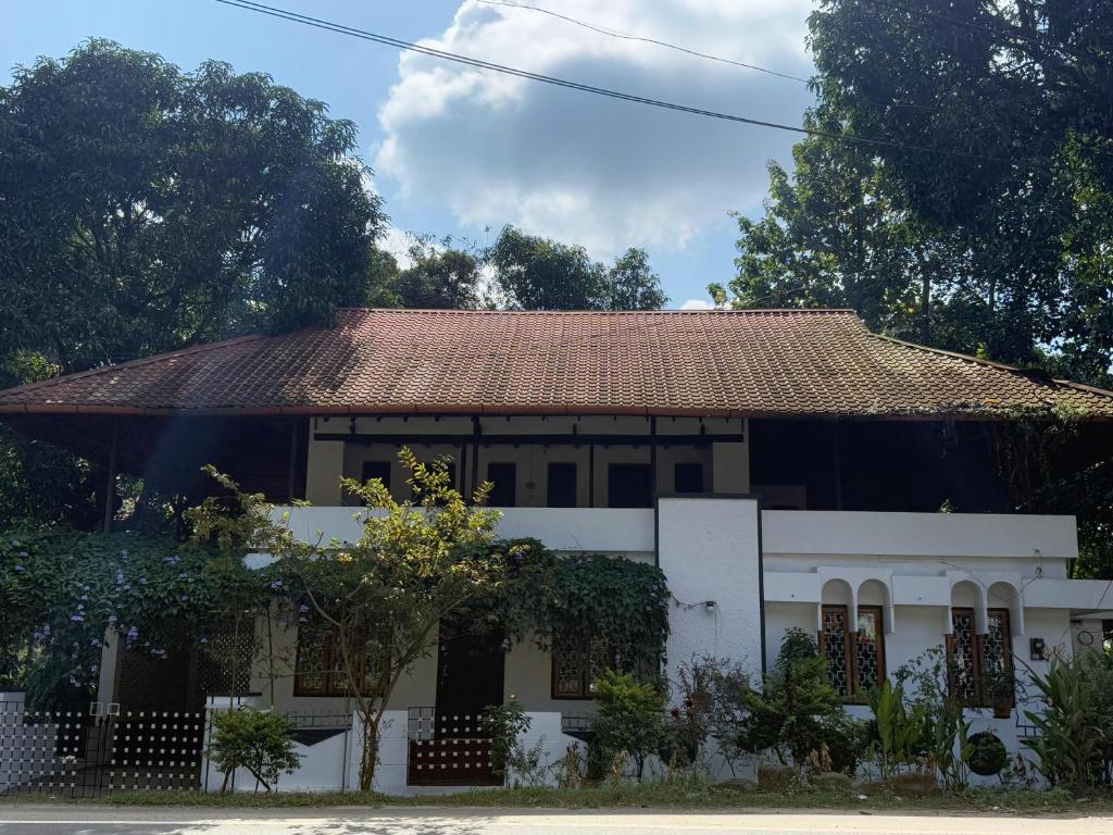 a white house with a rusty roof at Urban Minz in Mūvattupula