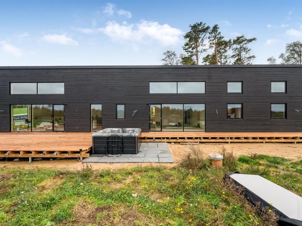 a black house with a wooden deck and a black building at Holiday Home Gillis - 1km from the sea by Interhome in Tvedhuse