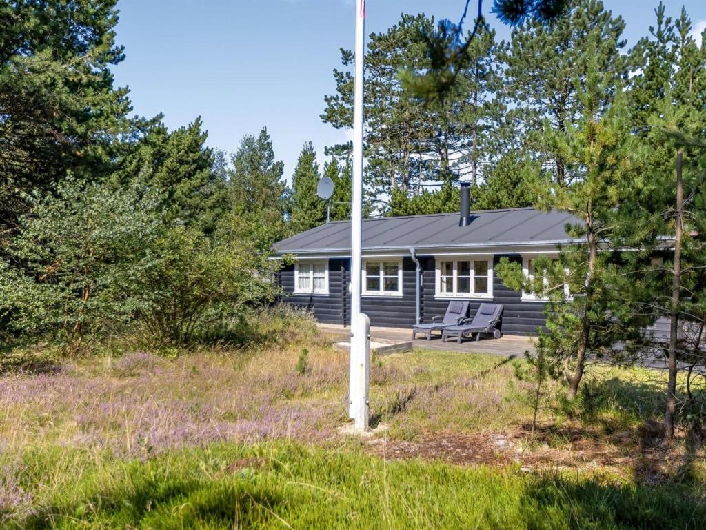a cabin in the woods with a bench in the yard at Holiday Home Reinhardt - 800m from the sea by Interhome in Mølby