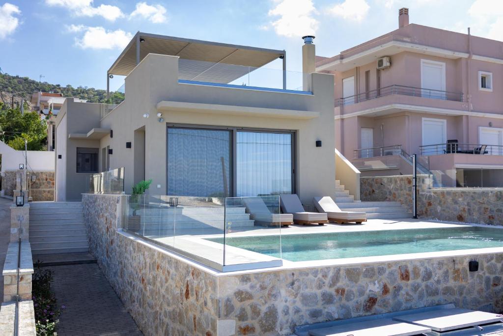 a villa with a swimming pool in front of a house at Ammos Luxury Villas Salamina in Aiándion