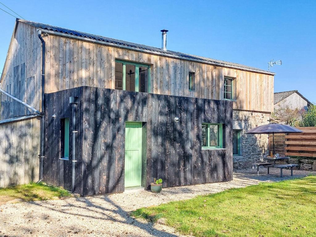 a wooden house with a green door in a yard at Holiday Home La Longère by Interhome in Trémaouézan