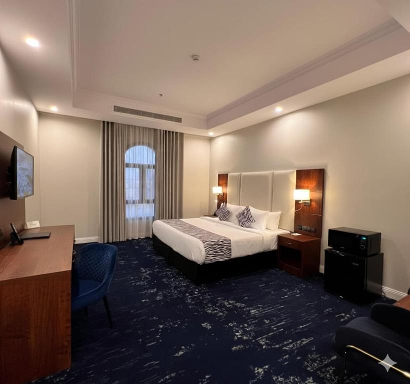 a hotel room with a king sized bed and a desk at Dancenter Jeddah Luxury Hotel in Jeddah