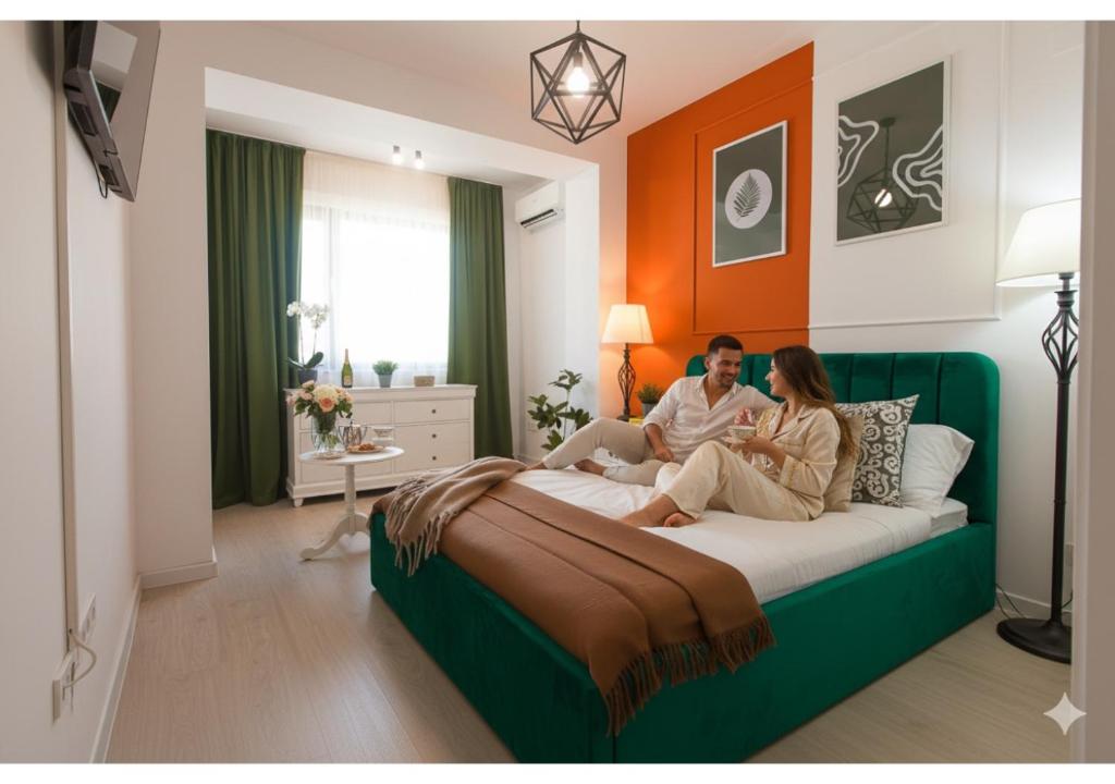 un homme et une femme assis sur un lit dans l'établissement Ivory Residence - Modern Minimalist Studio Apartment, à Bucarest