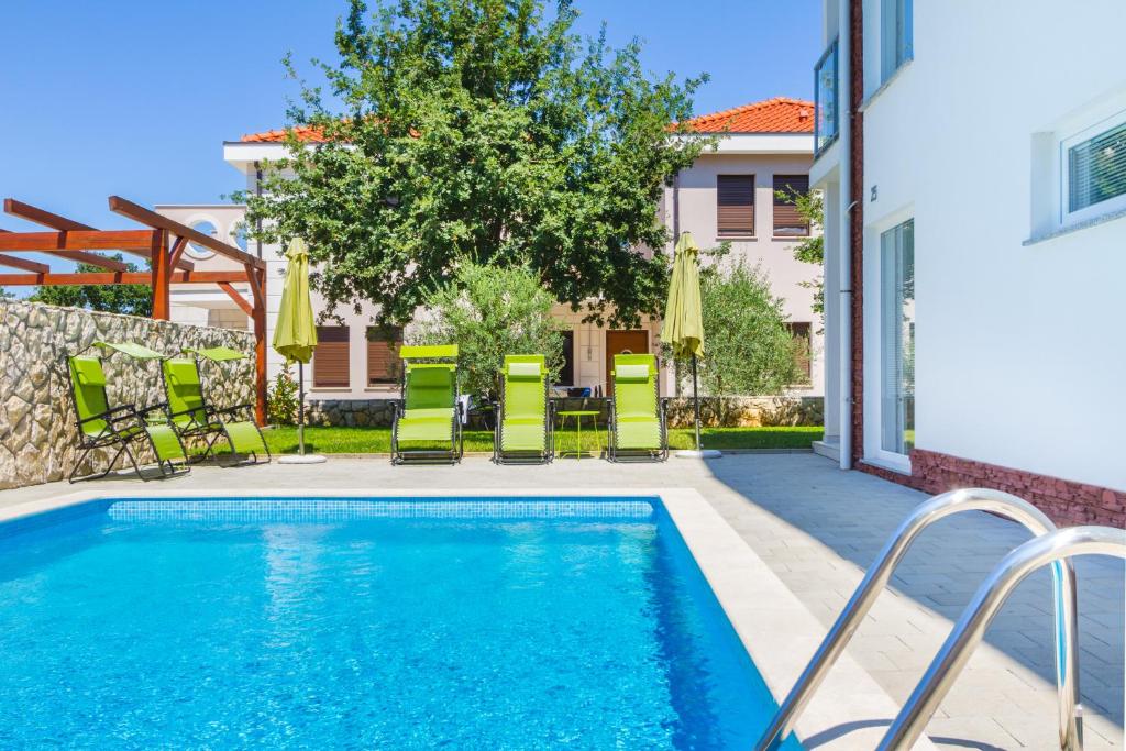 a swimming pool with lounge chairs and a house at Villa Apartments Futura in Vantačići