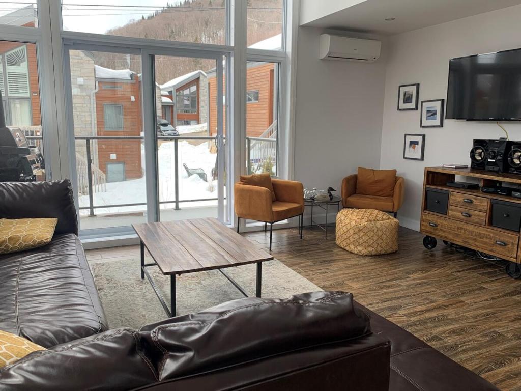 a living room with a couch and a table at Spa privé et billard pret de la montagne de ski Stoneham 12 personnes in Stoneham