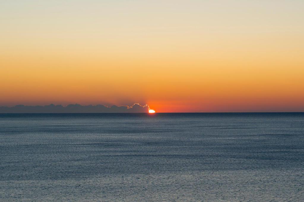 una puesta de sol sobre el océano con el sol en el horizonte en A peaceful holiday with a unique view, en Antalya
