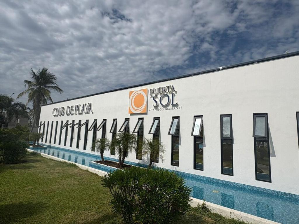 Barra ViejaEscapate a Acapulco Diamante,Depa familiar equipado的一座白色的建筑,设有游泳池和棕榈树