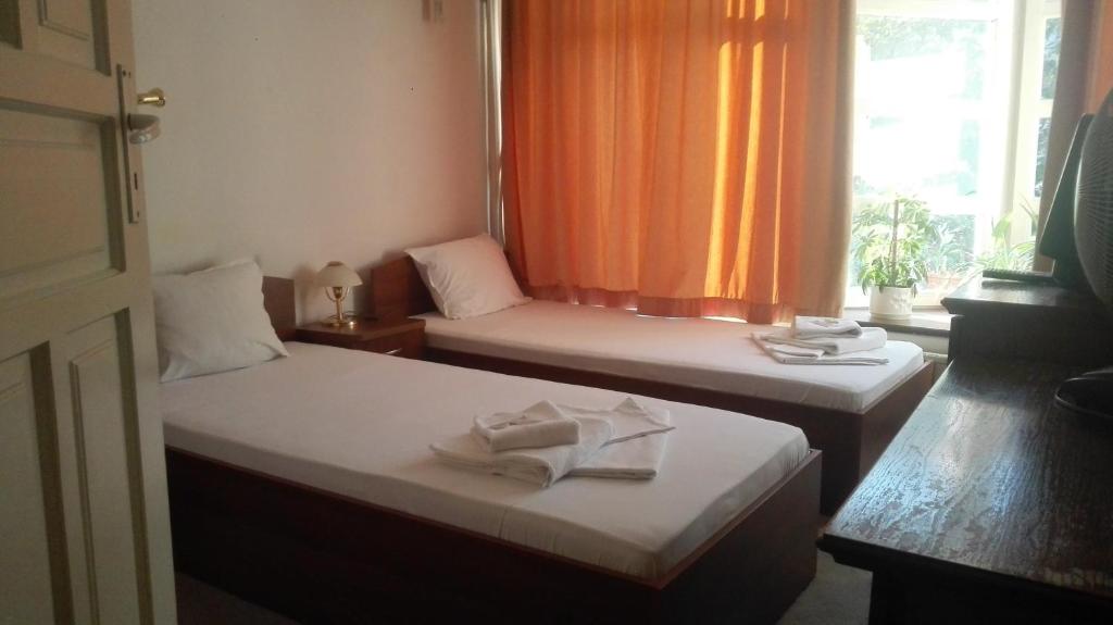 セヴリエヴォにあるFamily Hotel Rositsaのオレンジ色のカーテンが備わる客室のベッド2台