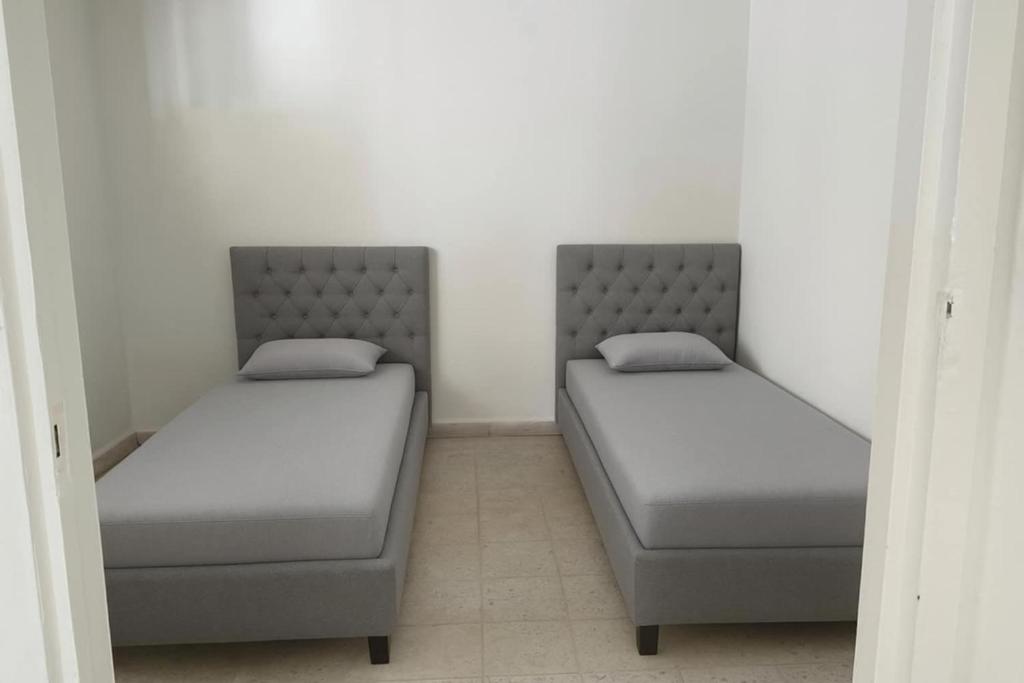 twee bedden in een kamer met witte muren bij Marsa home in Dar Tahar Zaouch