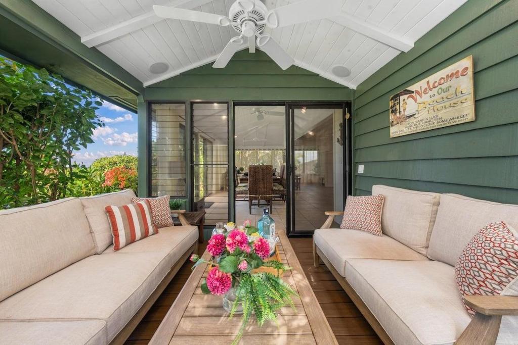 a porch with a couch and a table with flowers on it at International Colony Club 37 · ICC 37 Remodeled Hawaiian Cottage in Kaanapali