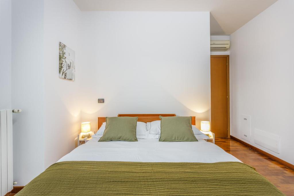 une chambre avec un grand lit blanc avec des oreillers verts dans l'établissement Parking & Free WiFi - Functional apartment, à Modène
