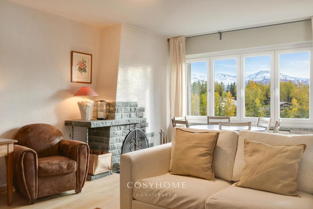 a living room with a couch and a fireplace at Alpine Sunset l Attique l Golf l By CosyHome in Crans-Montana