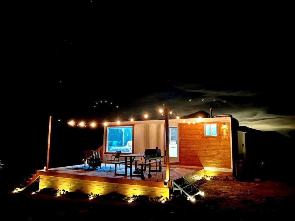 a small house with a table on a deck at night at Stunning Tiny House with Picnic Space, Barbecue and Fire Pit in Meadview, Arizona in Ray Place
