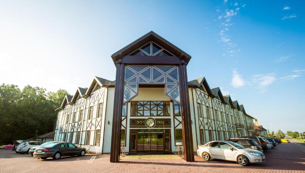 a large building with cars parked in a parking lot at Georg Park Hotel in Tarashany