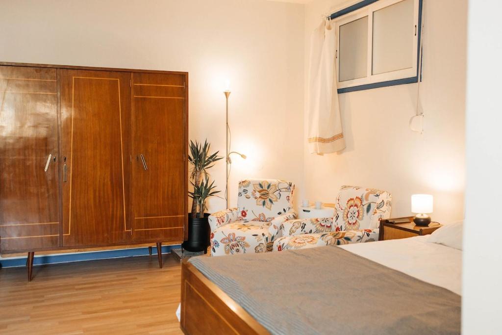 a bedroom with a bed and two chairs and a cabinet at Costa Cabral Porto Flat in Porto