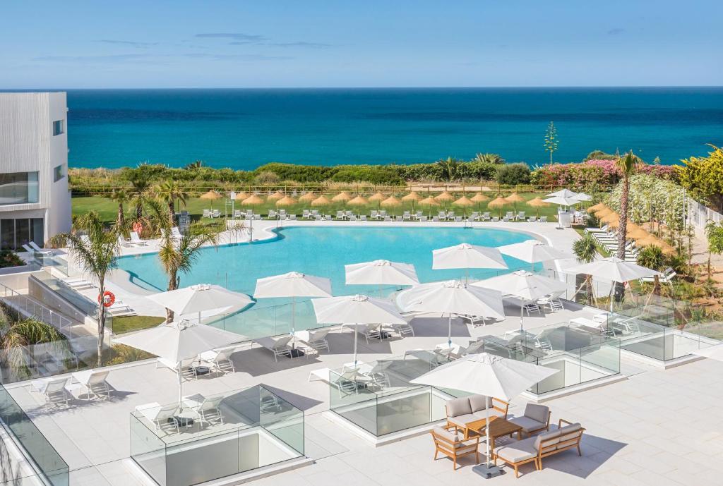 an image of a pool with umbrellas and the ocean at Grupotel Conil Playa - Adults Only Recommended in Conil de la Frontera