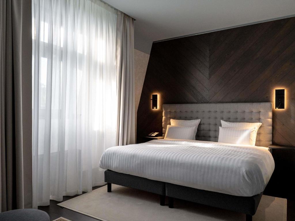 a bedroom with a large bed and a large window at Pullman Riga Old Town - Renovated 2025 in Rīga