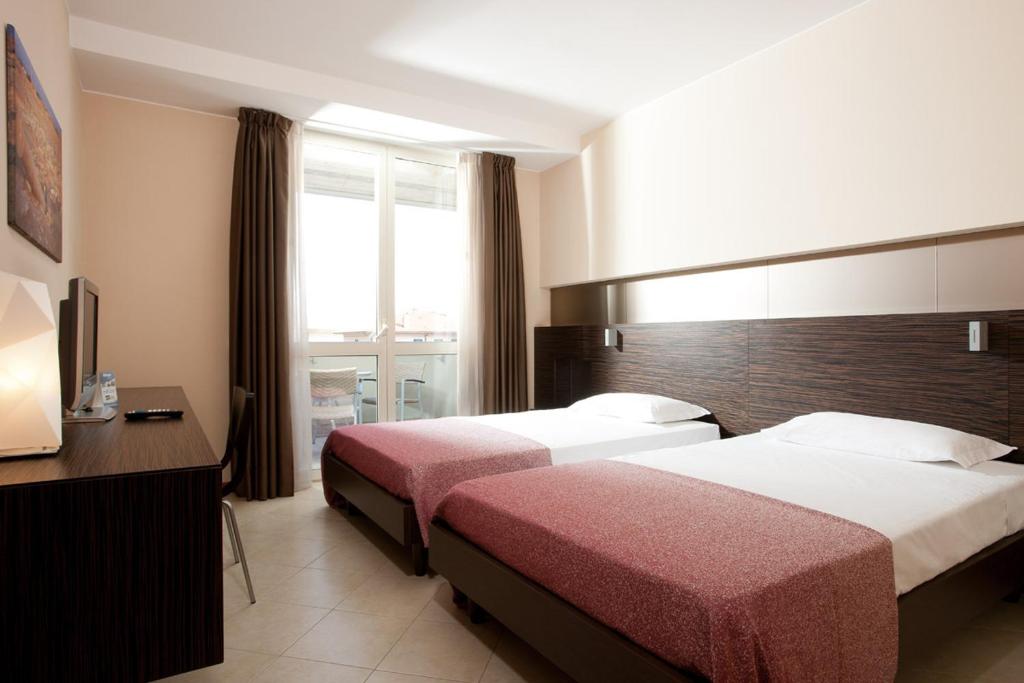 Rosso Frizzante في Sorbara: غرفة فندقية بسريرين ونافذة