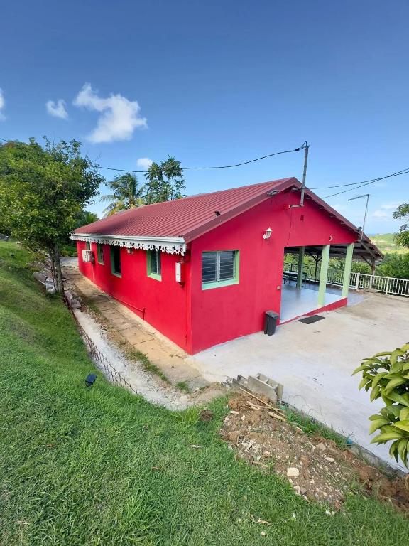 a red house with a red roof at Maison de charme au Robert avec spa et vue sur mer in Le Robert