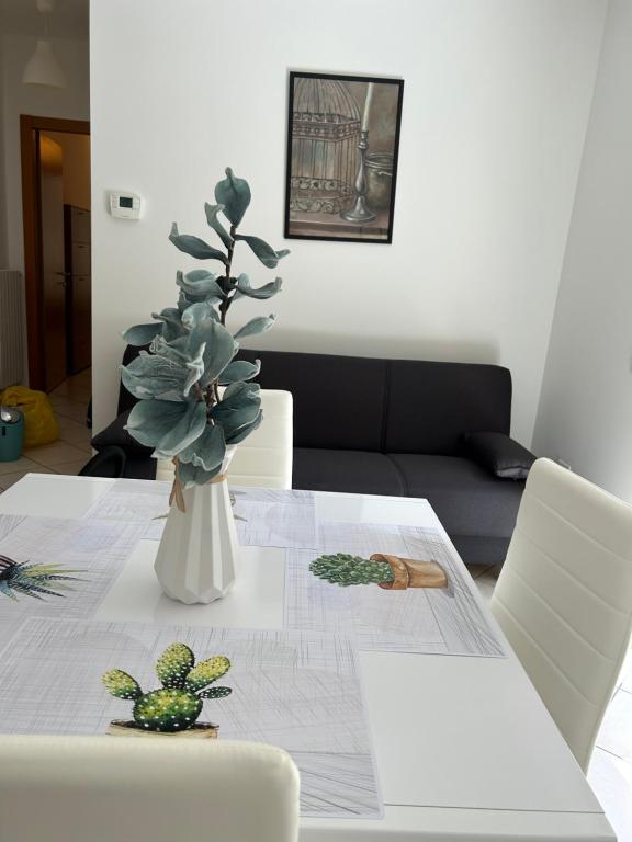 a table with a white vase with plants on it at Il Centro Apartments 2 in Salsomaggiore Terme