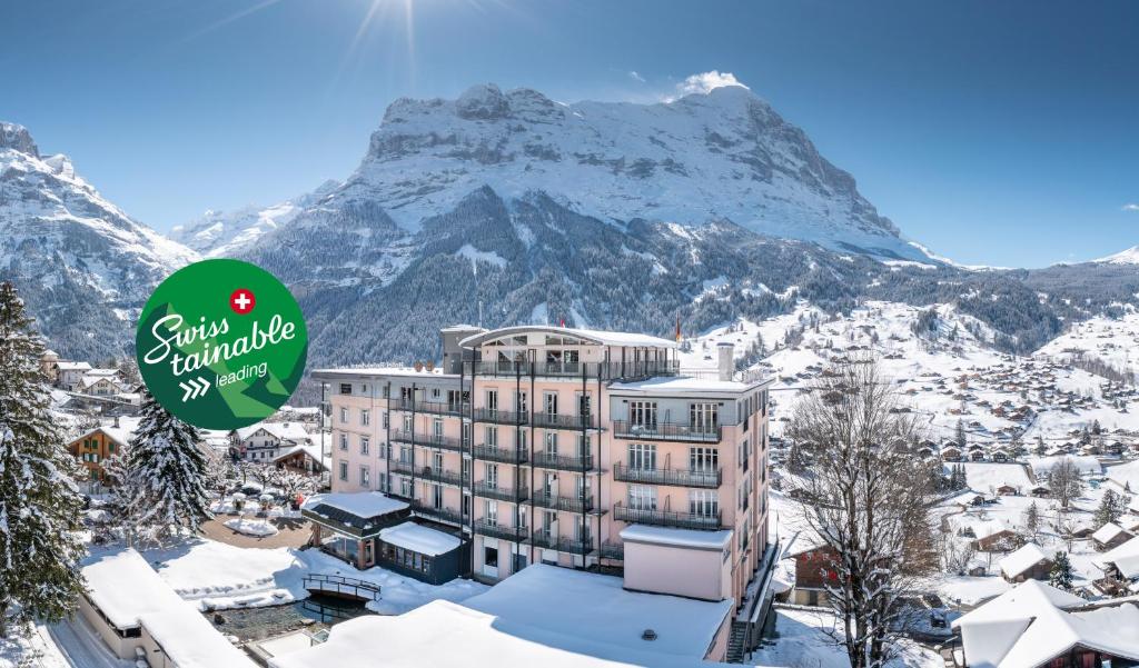 a hotel with a snow covered mountain in the background at Belvedere Swiss Quality Hotel in Grindelwald