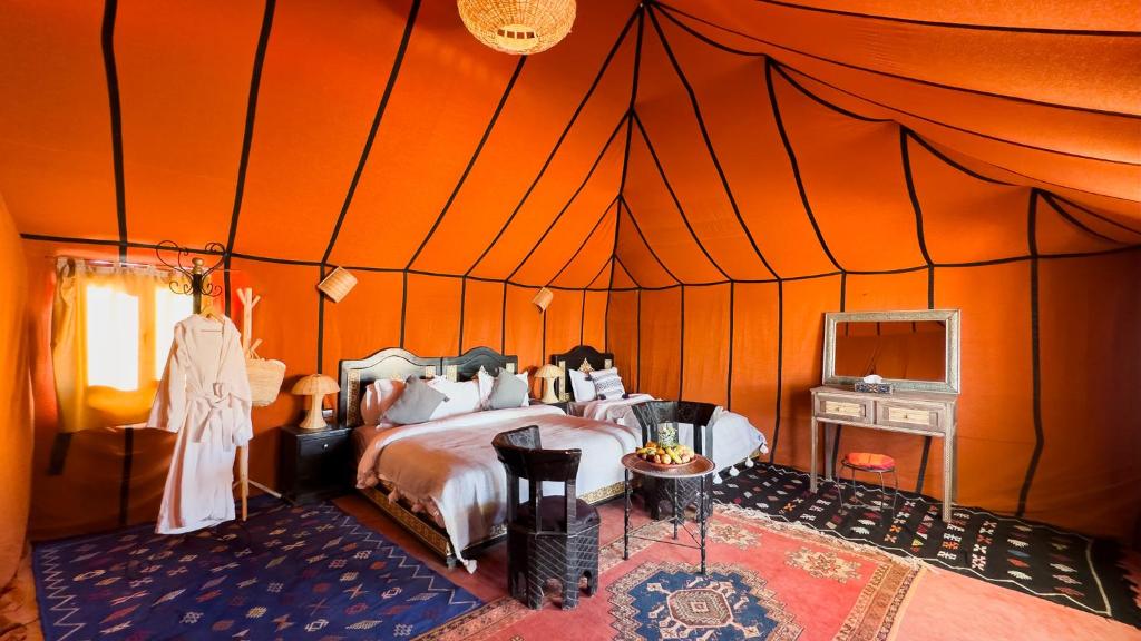 a bedroom with a bed in an orange tent at Alan Tent Merzouga in Merzouga
