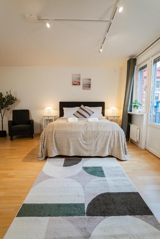 ein Schlafzimmer mit einem Bett und einem Teppich auf dem Boden in der Unterkunft Warm Modern Studio in the Heart of Linné & Haga in Göteborg