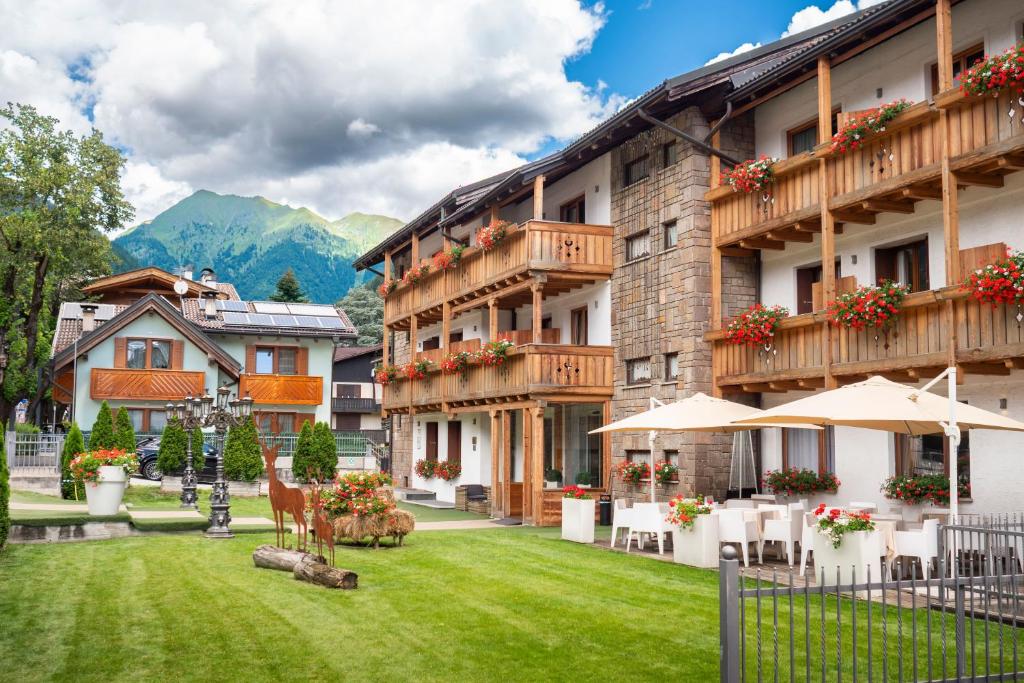 ein Hotel mit einem Rasen vor dem Gebäude in der Unterkunft Olympic regina hotel in Pinzolo
