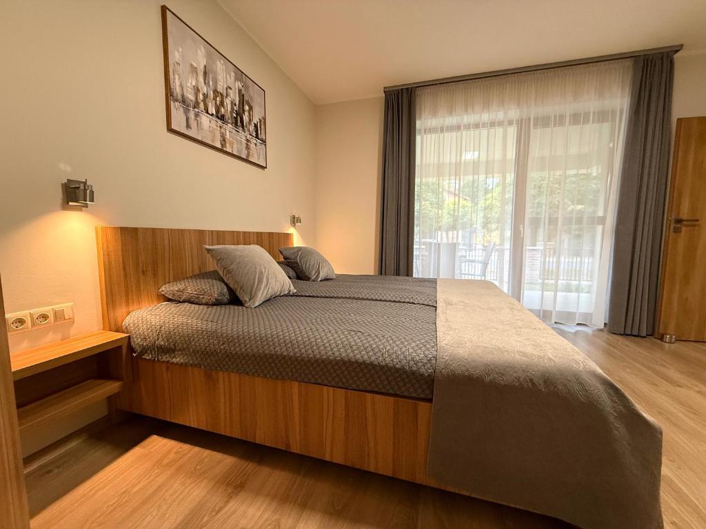 a bedroom with a large bed and a window at Hídfő Apartman in Gyula