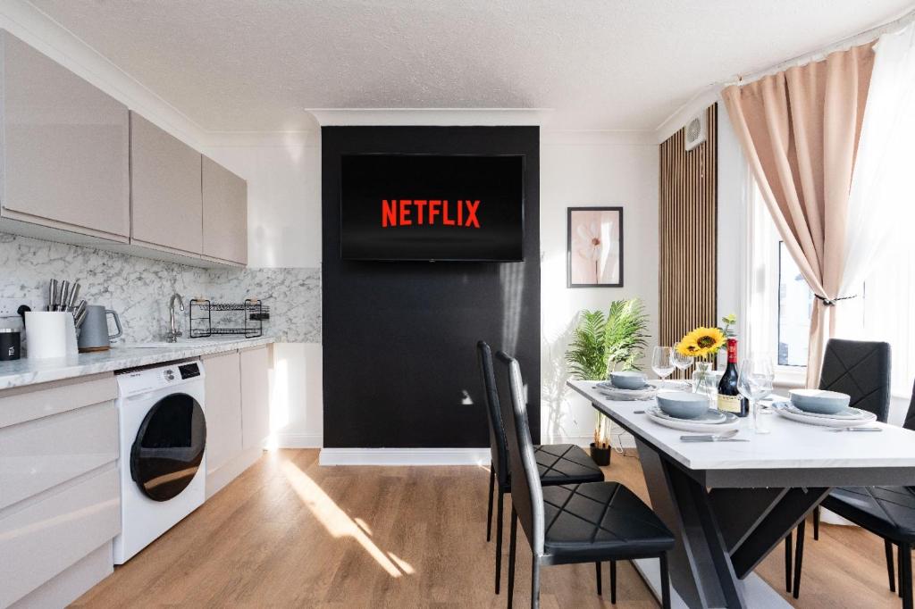 a kitchen with a table and a sign that reads netflix at Open Mind Property - Cozy 4BR Flat & 12 Guests in Littlehampton