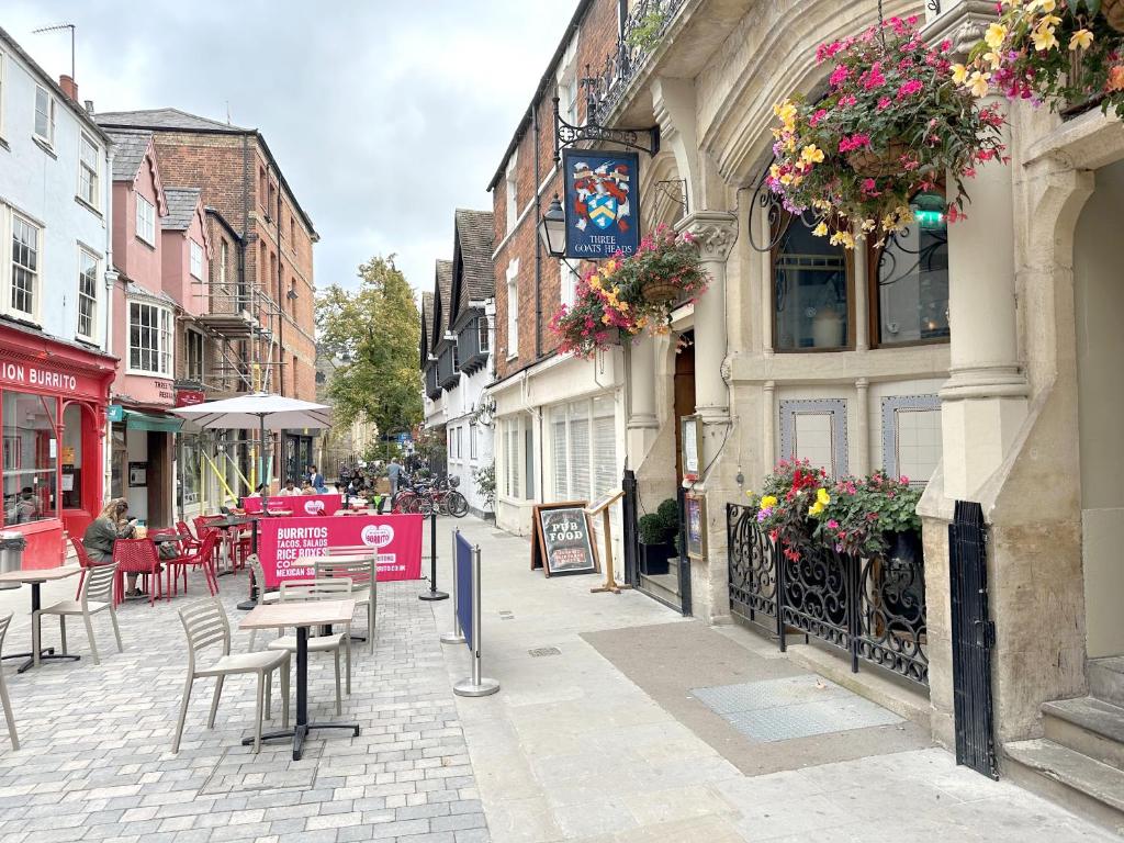 eine Stadtstraße mit Tischen, Stühlen und Gebäuden in der Unterkunft Apartment next to The Oxford Union in Oxford