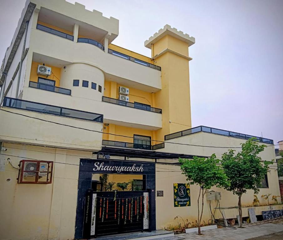 un edificio alto amarillo con una puerta delante de él en SHAURYAAKSH HOTEL & Home stay, en Jaipur