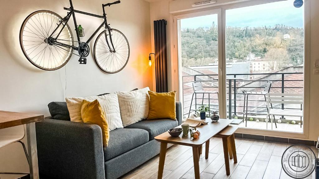 a living room with a couch and a bike hanging on the wall at Au Petit Vélo - Appart Vue sur la Bâtie - Parking Gratuit & Calme - Vienne in Vienne