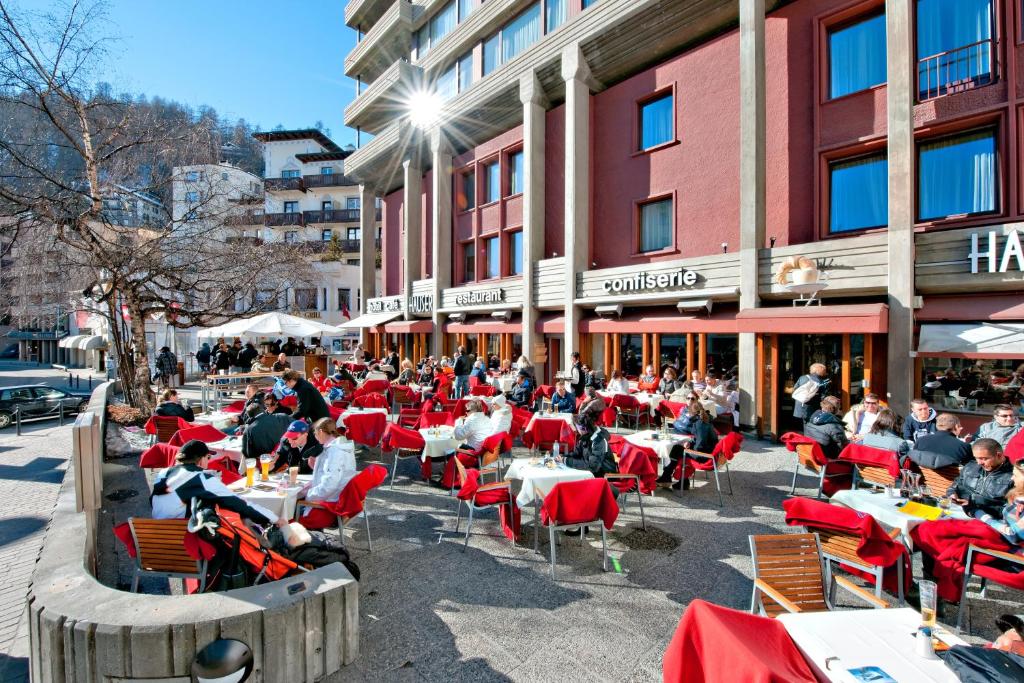 a group of people sitting at tables in front of a building at Hauser Hotel St. Moritz in St. Moritz
