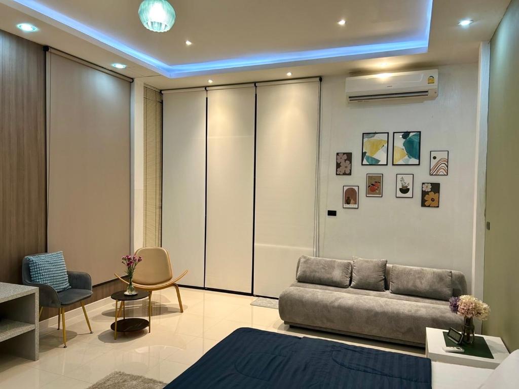 een woonkamer met een bank en stoelen bij Ellie House Phuket Old Town in Ban Rangeng