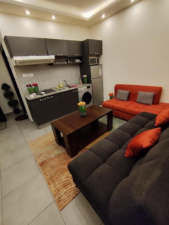 een woonkamer met een bank en een keuken bij Gentle Breeze Studio 3 in Amman